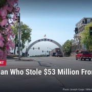 Galena Avenue in downtown Dixon, Illinois, with the city's arch in the distance and pink flowers in the foreground, with headline: The Woman Who Stole $53 Million From Her Own City